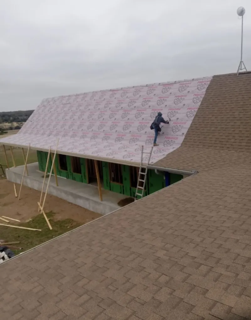 Worker preparing underlayment for a metal roof installation in Hillsboro